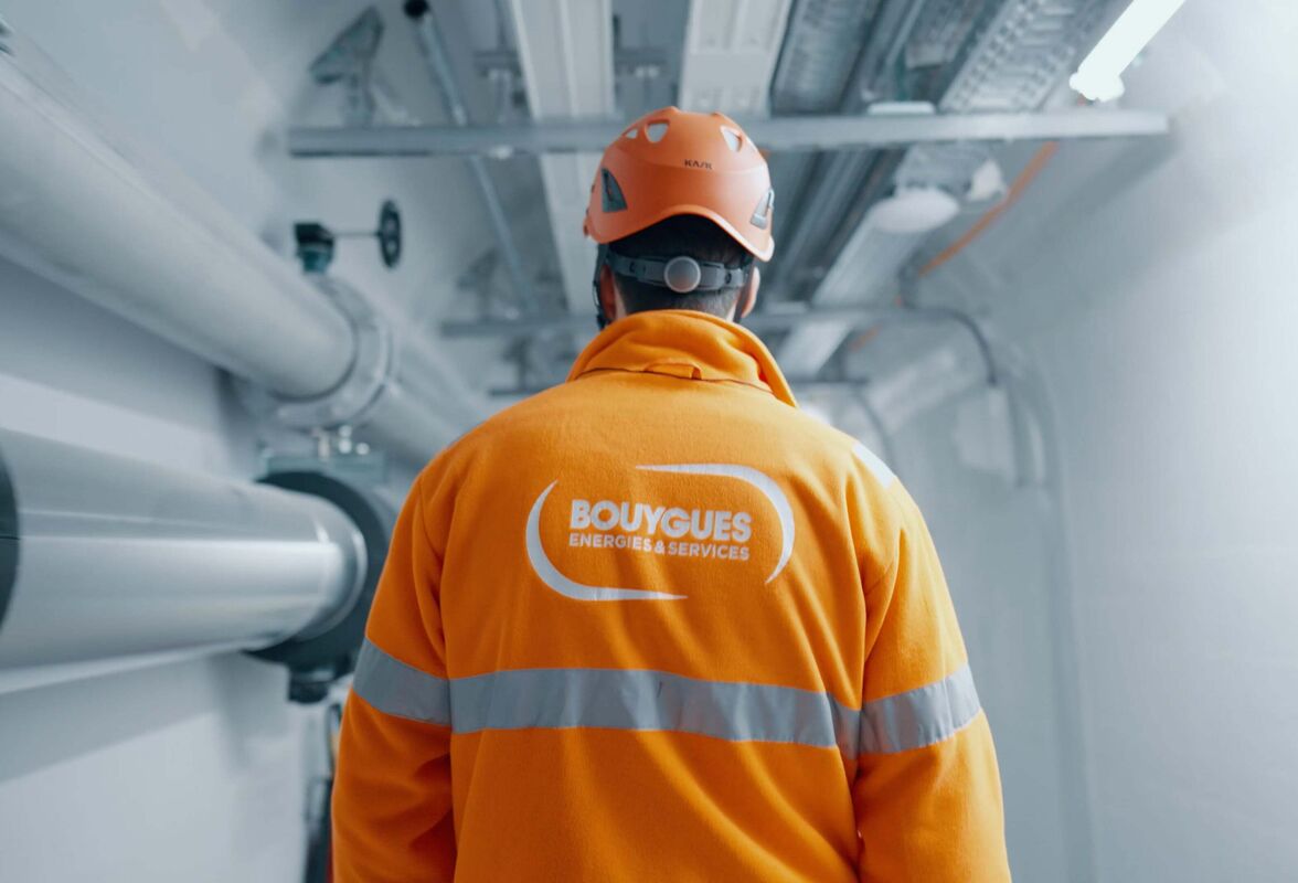 Filmstill aus dem Bouygues Energies & Services Imagefilm – Techniker im orangenen Schutzanzug im Rechenzentrum-Stollen Luzern, produziert von CORPMEDIA als Employer Branding und Image-Storyworld.