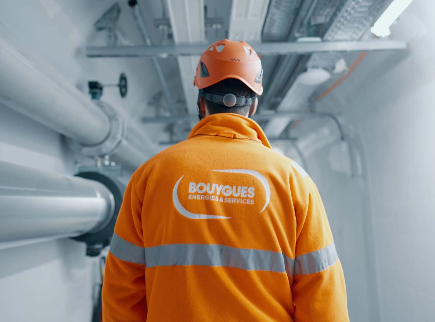 Filmstill aus dem Bouygues Energies & Services Imagefilm – Techniker im orangenen Schutzanzug im Rechenzentrum-Stollen Luzern, produziert von CORPMEDIA als Employer Branding und Image-Storyworld.