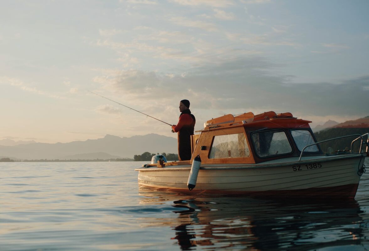 Schauspieler Philippe Graff als Fischer auf dem Zürichsee bei Sonnenaufgang – Szene aus der modularen Raiffeisen Zürisee Storyworld von CORPMEDIA.