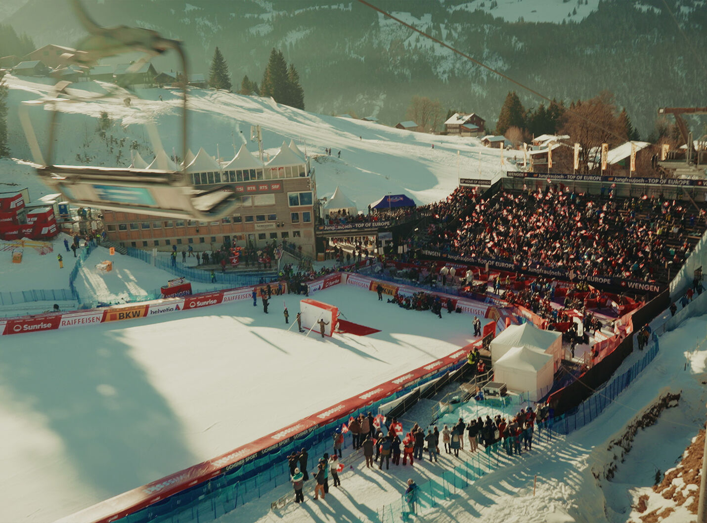 Filmstill aus dem TOITOI Lauberhorn Dokumentarfilm für Hidden Champions – Zieleinfahrt des legendären Lauberhornrennens in Wengen mit vollbesetzter Tribüne, aufgenommen von der Sesselbahn, produziert von CORPMEDIA.