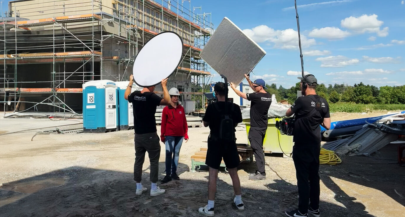 CORPMEDIA Filmcrew mit Reflektor und Kamera auf der Baustelle – Rahmenhandlung des TOI TOI Films, produziert vor Ort auf einer Schweizer Baustelle.