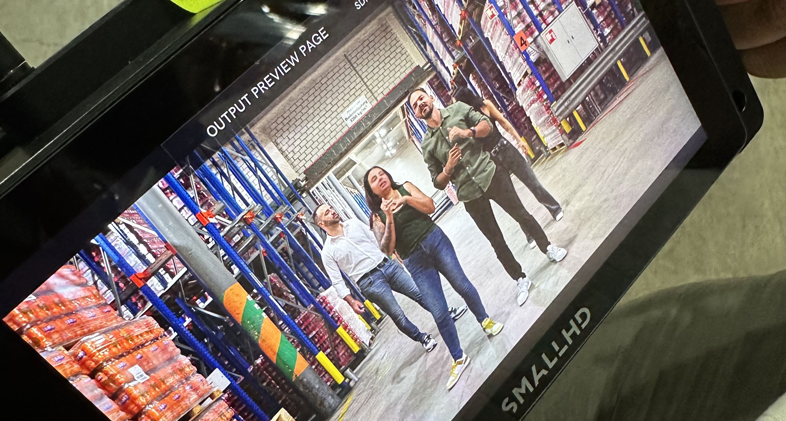 Drei Coca-Cola HBC Protagonisten auf dem SmallHD Regiemonitor beim Heroshot in der Lagerhalle in Brütisellen – Behind the Scenes des CORPMEDIA Employer Branding Films, in 8.6K produziert für die internationale HBC Gruppe.