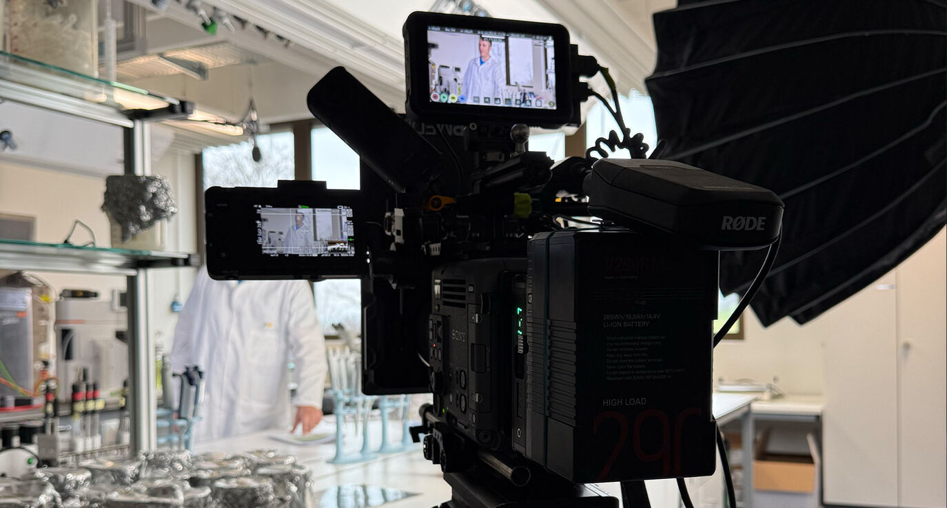 Behind the Scenes im Mikrobiologie-Labor der ZHAW Wädenswil – Sony Burano mit Regiemonitor beim Recruiting Storyworld-Drehtag von CORPMEDIA, Protagonist im Laborkittel im Hintergrund sichtbar.